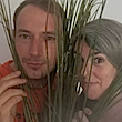 Two faces, a man and a woman look from behind a set of straws.