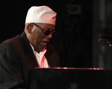 A man smiles while sitting at a piano