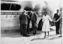 Freedom Riders gather with authorities alongside their burning bus after a mob attack outside Anniston, Alabama. Photo courtesy of Firelight Media