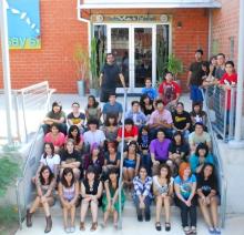 Students sitting on stairs in front of building.