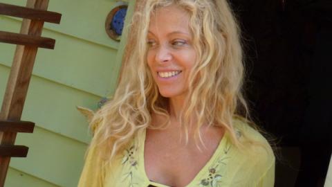 a woman with blonde wavy hair against a green shingled background