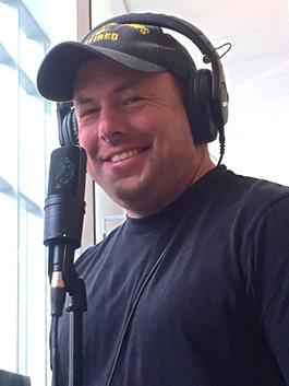 Michael Schneider wearing headphones and ready at the microphone