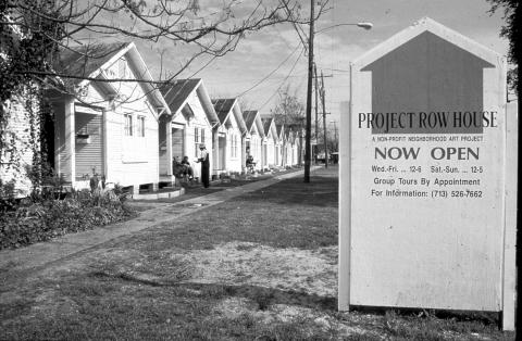 A sign to the right  and a row of houses to the left. 