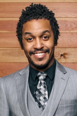 Portrait of Black man with moustache wearing a gray suit. 