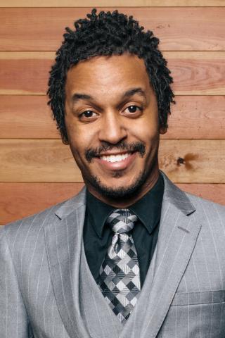 Portrait of Black man with moustache wearing a gray suit.