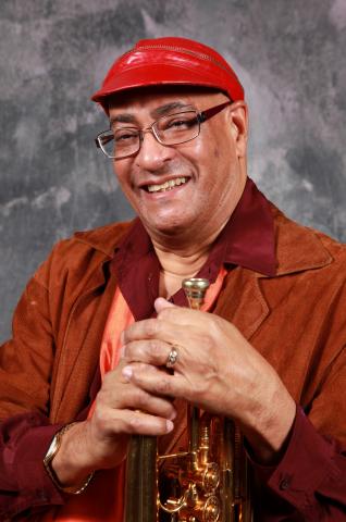 Portrait of man in red hat holding trumpet. 