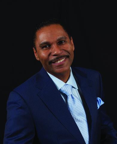 Portrait of a middle-aged Hispanic man with short dark hair and moustache wearing a blue suit.