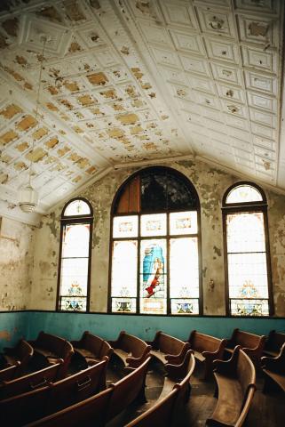 The interior of a dilapidated church, looking toward the stained glass. 