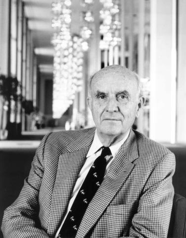 Portrait of balding man in suit with Kennedy Center hall behind him.