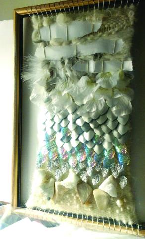 A piece of woven abstract art with blue and yellow and white colors prominent.