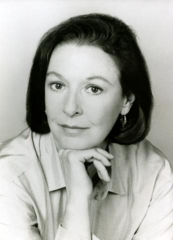 Portrait of white woman with short, dark hair, with her hand underneath her chin. 
