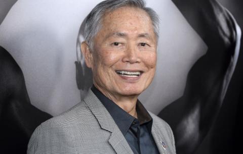 Portrait of Japanese American man wearing gray suit jacket over black shirt.