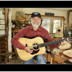 a man holding a guitar in his luthier's workshop