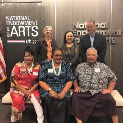 Two rows of people standing in front of the NEA sign