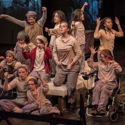 A group of bedraggled children perform as orphans in a production of Annie