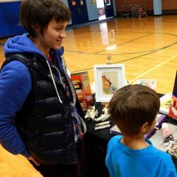 A woman artist talks to a young boy as he looks at one of her paintings provided by Art Mobile of Montana