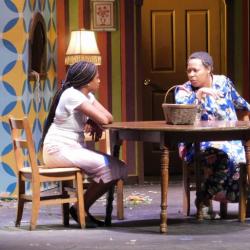 Two actresses sit at a table onstage in a production of August Osage County