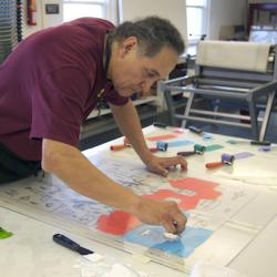 Artist Jim Denomie working in the printmaking studio at Crow's Shadow