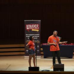 a group of four students on a stage with festival banners behind them