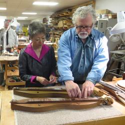 Man and woman examine a dulcimer