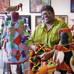 African-American woman surrounded by quilts.