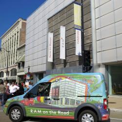 A colorful bus parked in front of a museum.