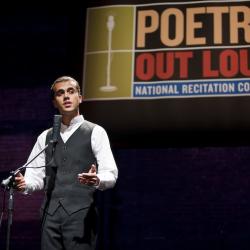 A young man stands behind a microphone mid-performance. A banner saying Poetry Out Loud is visible above his head