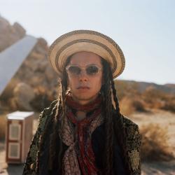 Photo of a man wearing sunglasses and a hat in the dessert