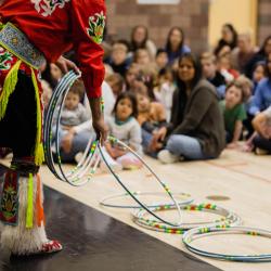 Native man performing a Hoop dance at an elementary school.