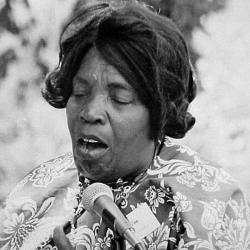 Woman sings into a microphone.