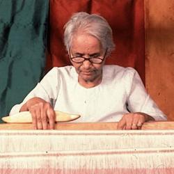 A woman sitted at a loom.