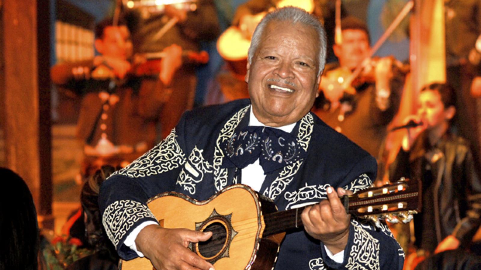 Man playing the guitar with a band behind him