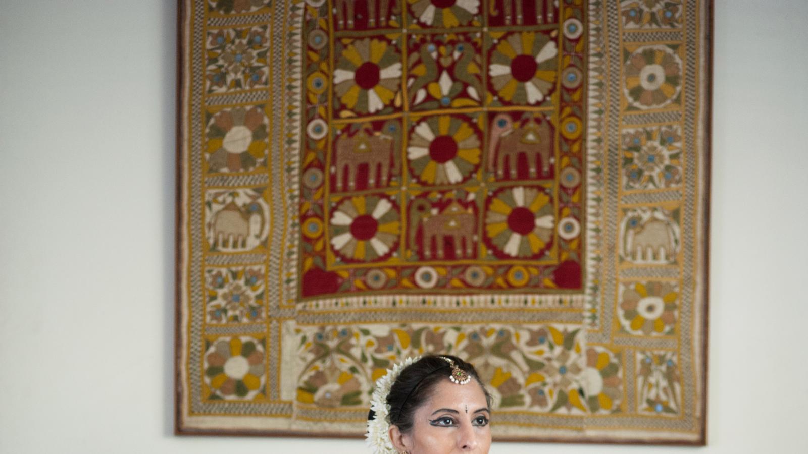 Anila Kumari A woman in classical Indian dress seated amongst colorful pillows strikes the pose of the goddess Devi