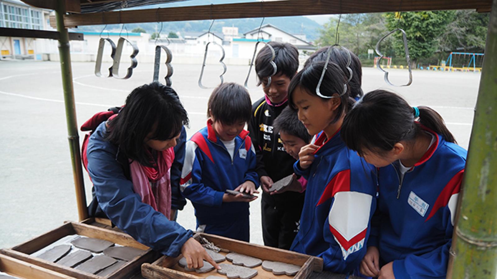 Children in Japan look inside a kiosk where clay cut-outs are laid out