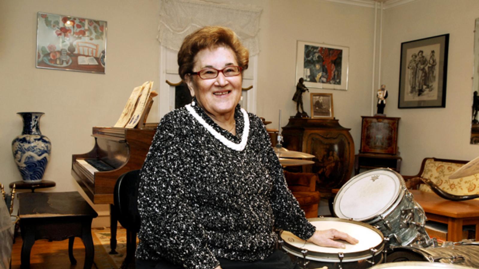 A woman sits in front of a drum set