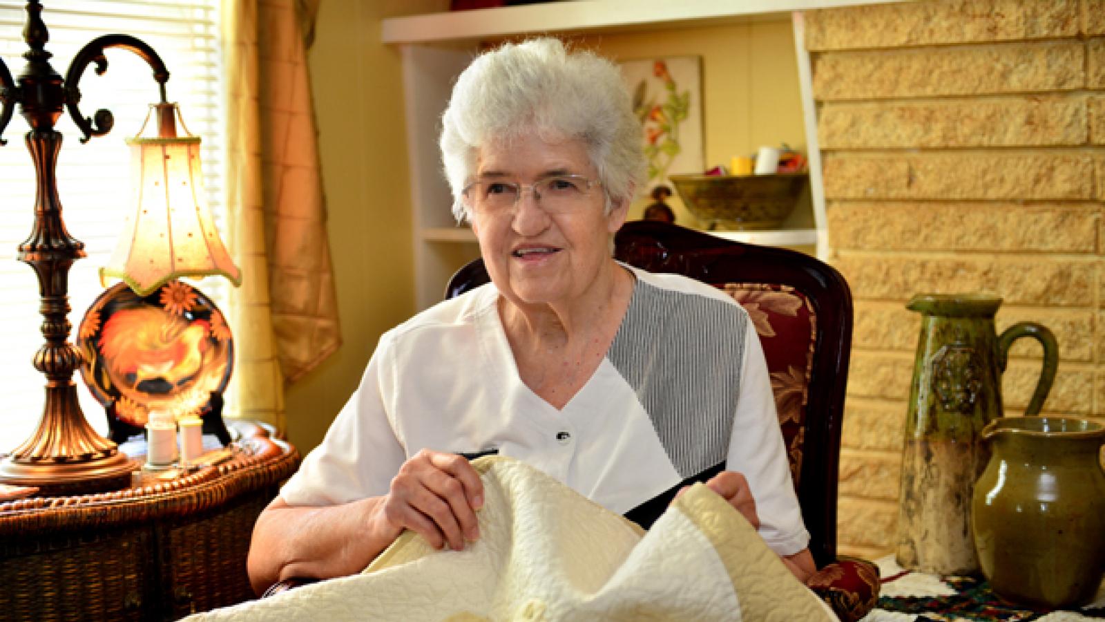 A woman sitting in a chair holds a quilt