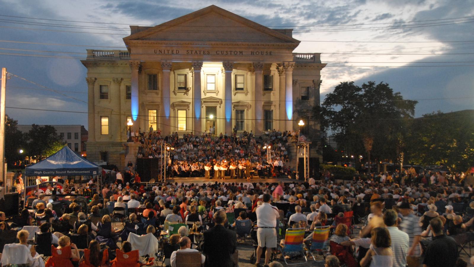 crowd of people sitting and watching evening music concert