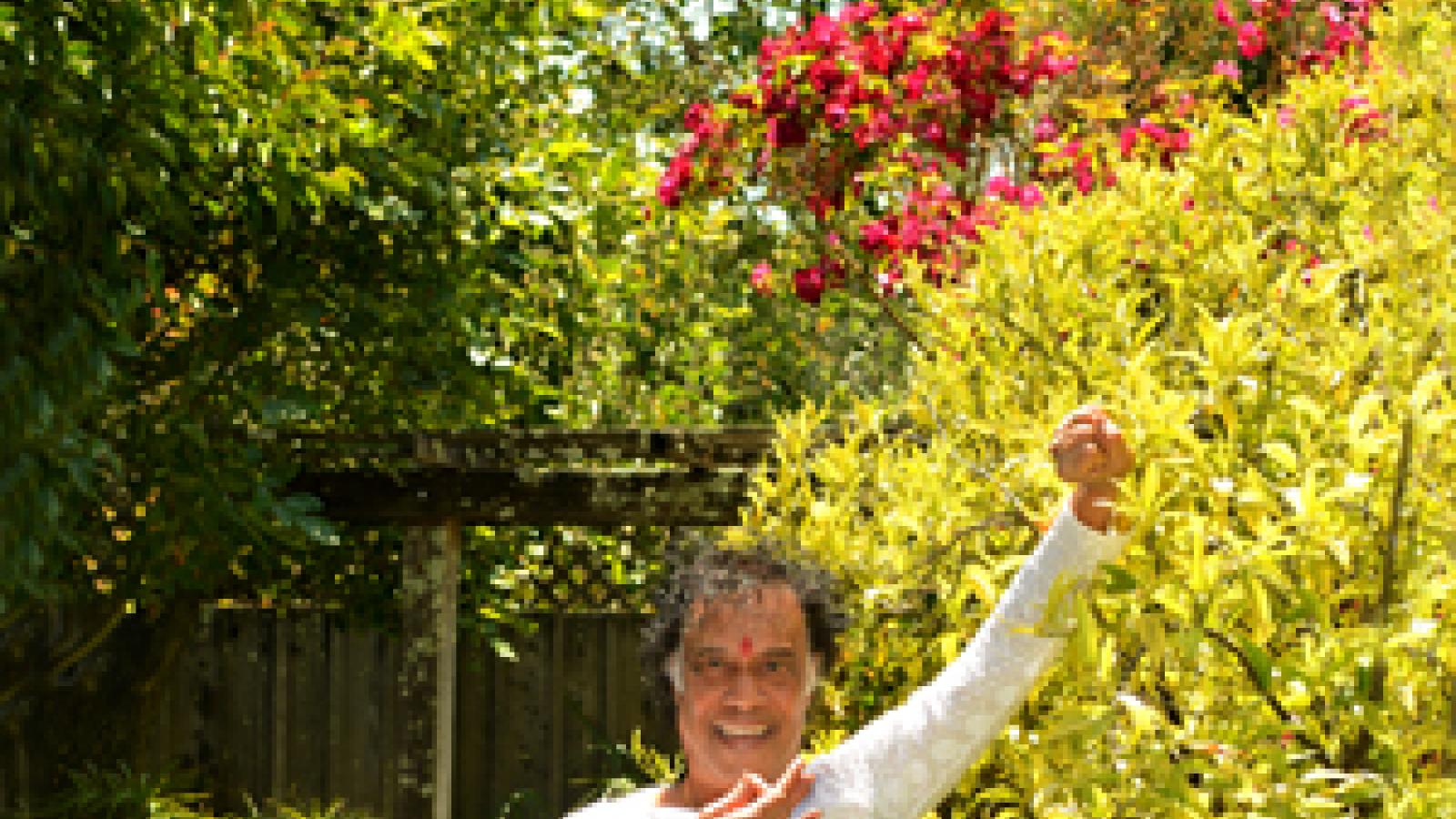 Chitresh Das A man dressed in white balances on one leg in a garden.