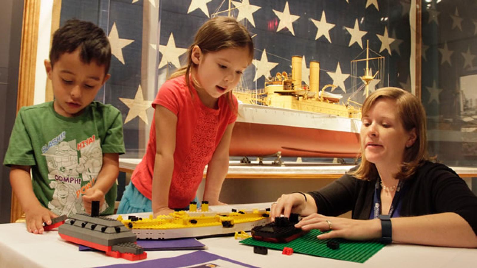 Woman with two children at a table buildig lego ships