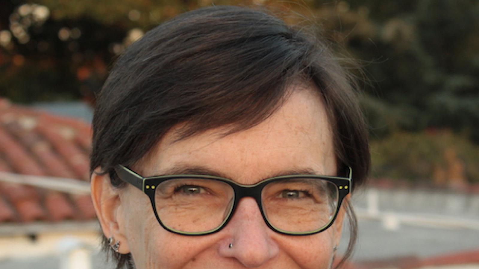 a white woman with short hair, a nose stud,  and glasses