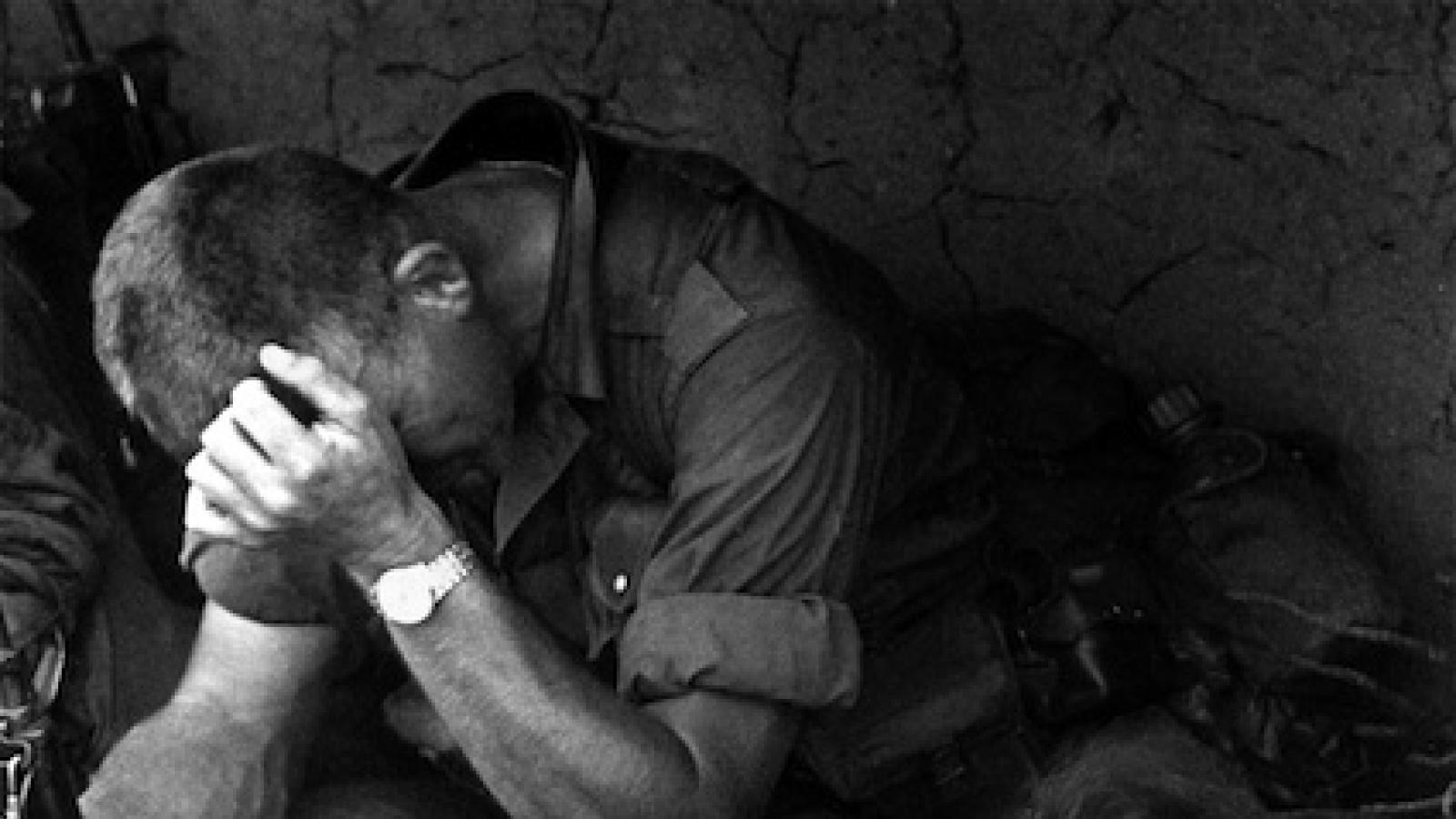 A Vietnamese villager clutches her hat and an American soldier leans a weary hand on his head as they sit together after a battle with the Viet Cong, 290 miles from Saigon, February 5, 1966.