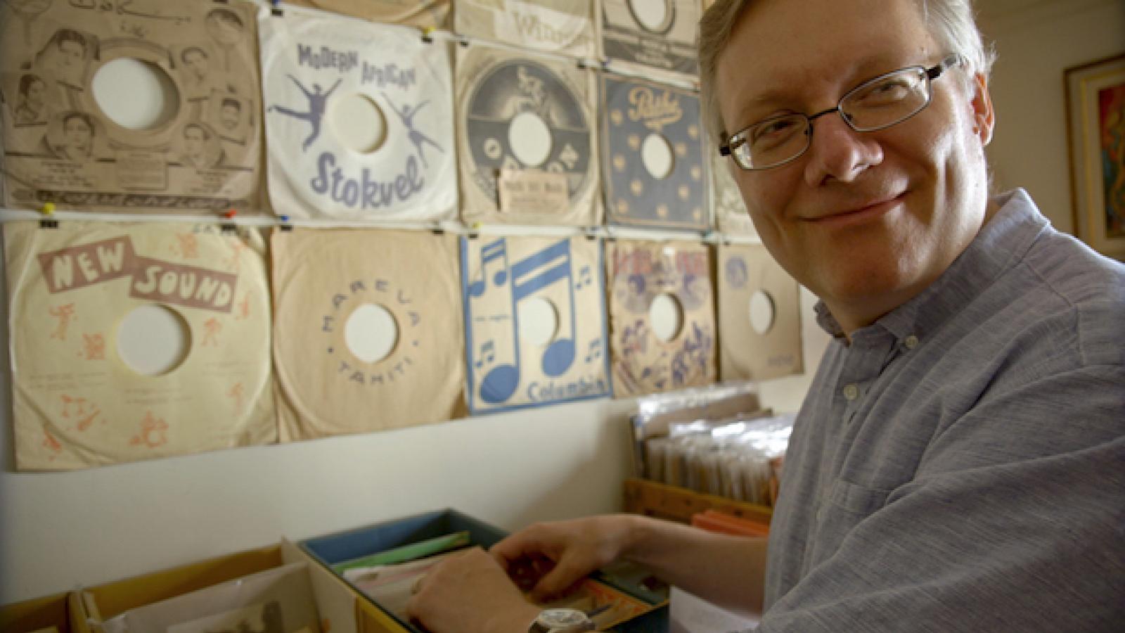 an older man with glasses in a record store with crates of records