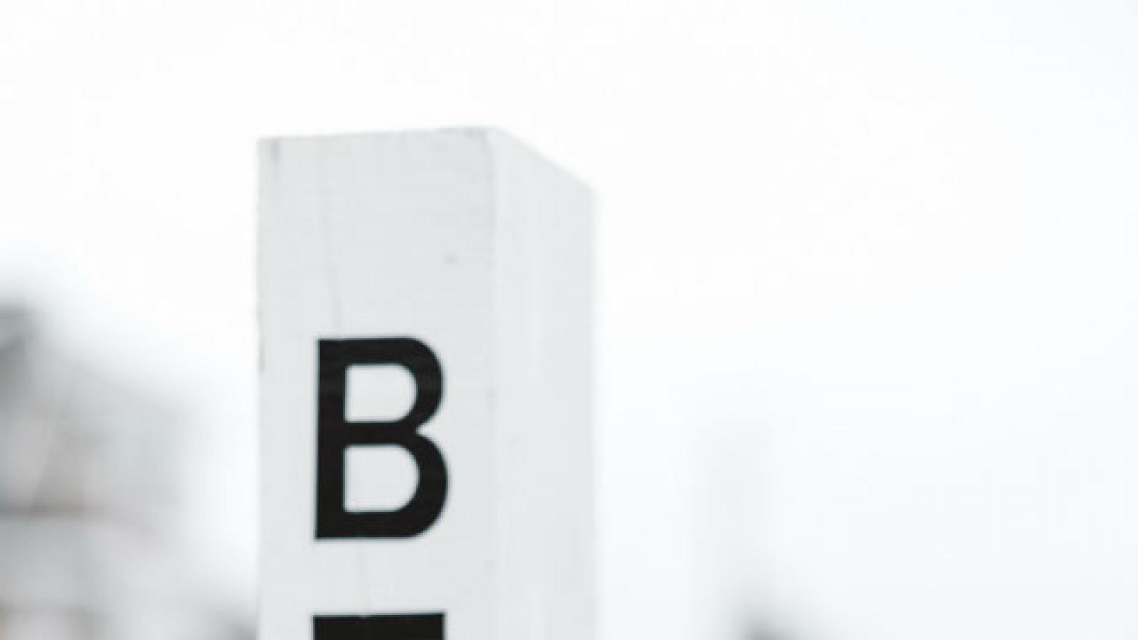 Skateboard leaning against post that says beach with headphones hanging on it