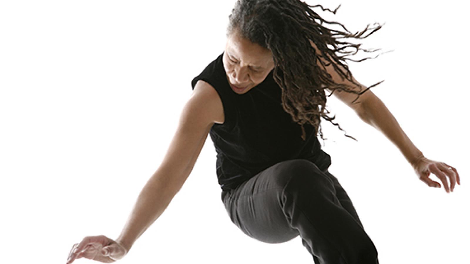 An African-American woman searing a sleeveless black shirt dancing with her eyes closed.