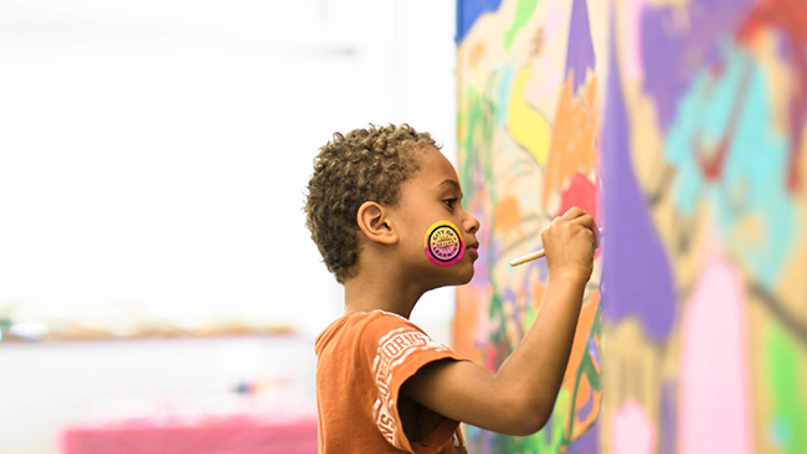 A little boy painting a mural