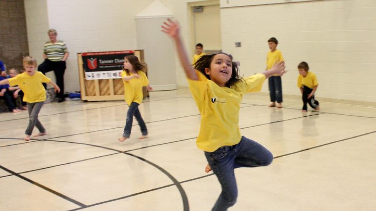 The Side by Side program from Tanner Dance Children wearing t shirts dance in a school recreation room