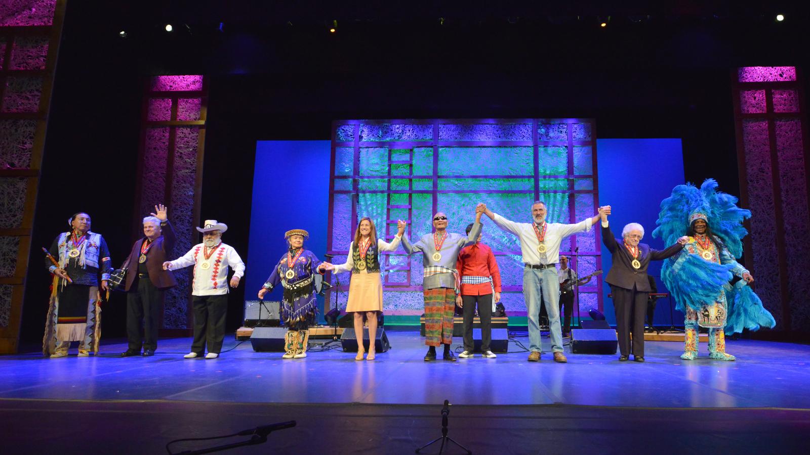 All honorees standing on stage waving to the audience and smiling.