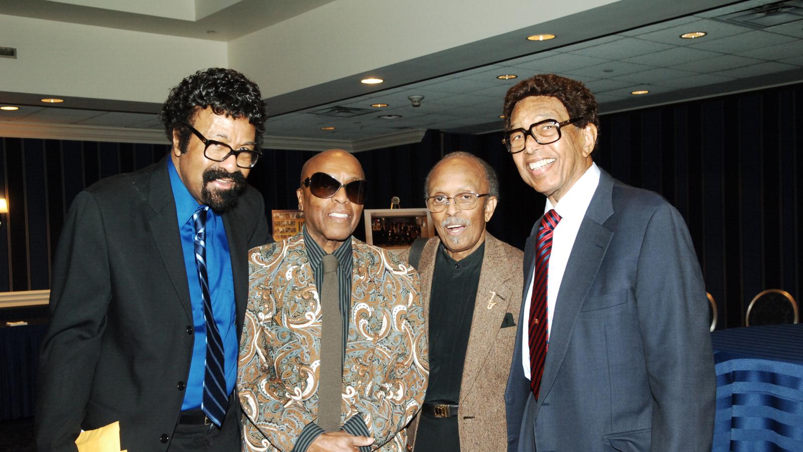 Four men stand together in a hotel ballroom