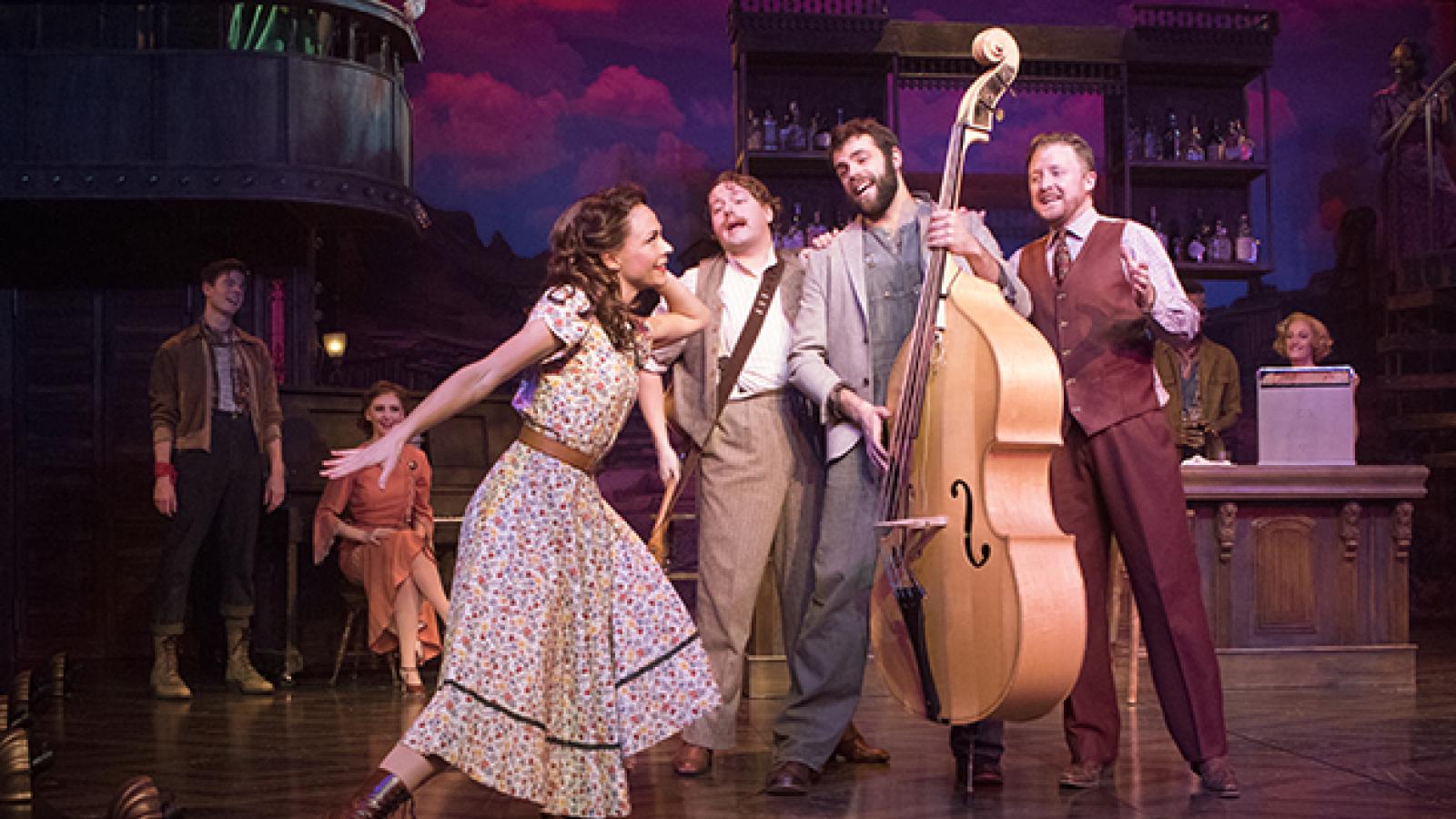 Actors and actresses with an upright bass perform onstage