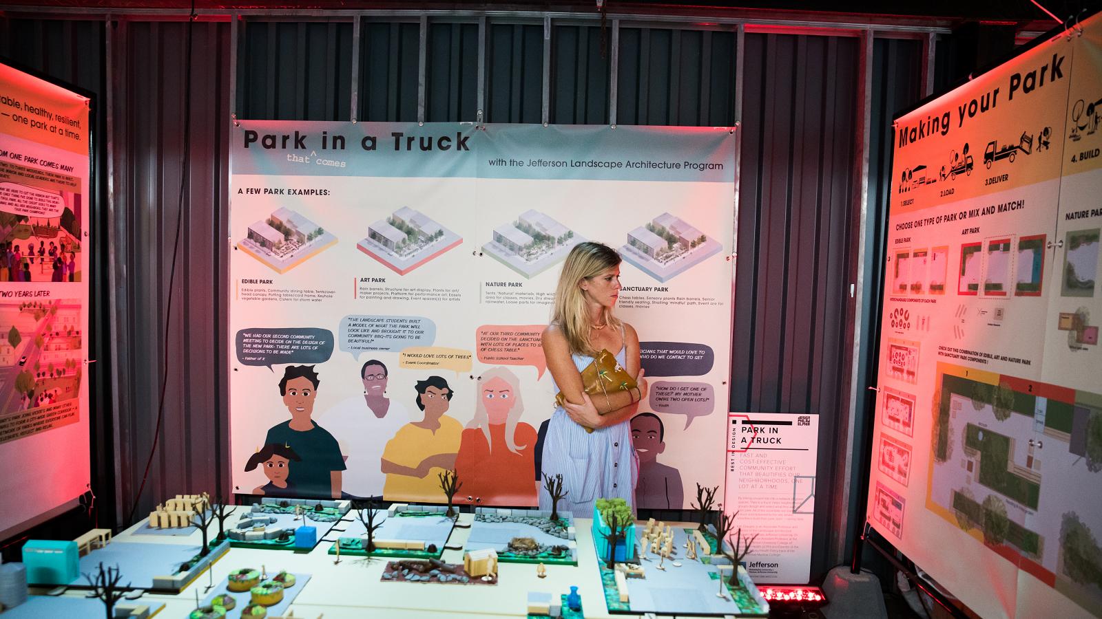 A woman looks at a series of large posters as part of a design exhibit